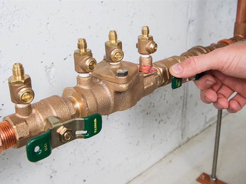 Image of a person turning a knob on a backflow preventer